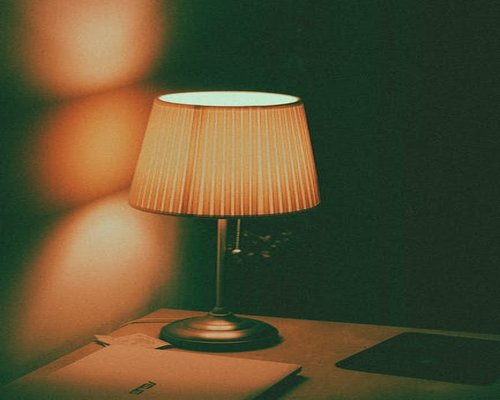 A warm desk lamp illuminating an open notebook on a wooden desk at night